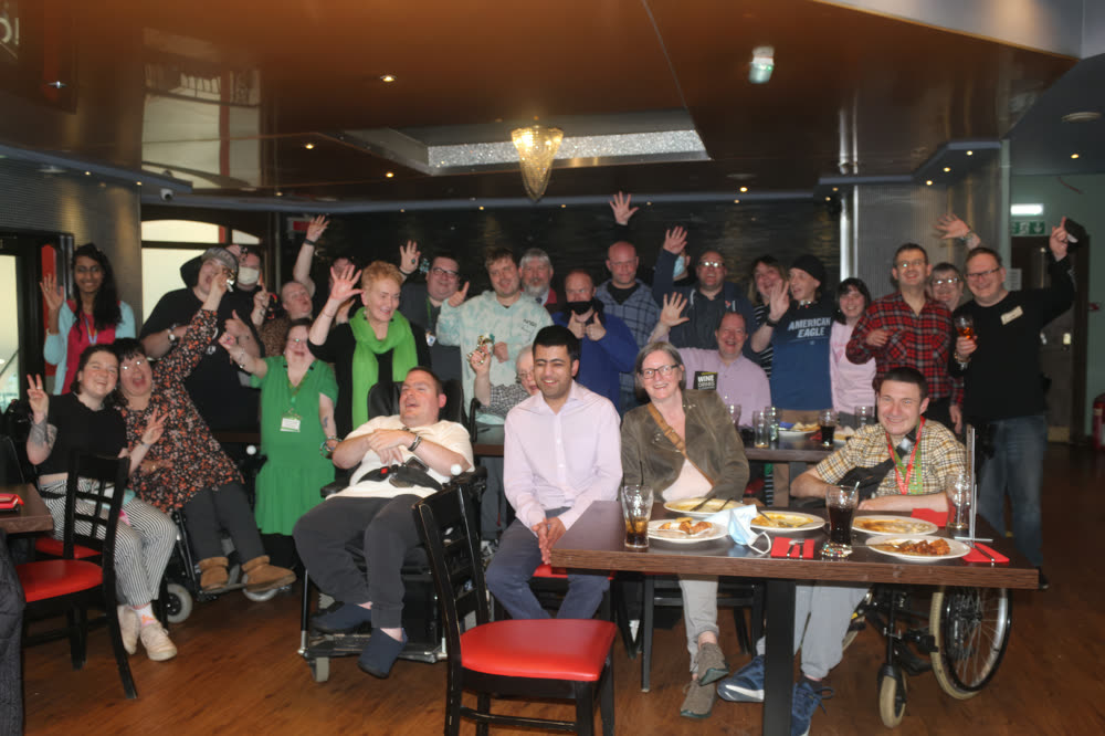 A big get2gether lunch — members around restaurant tables with their hands in the air